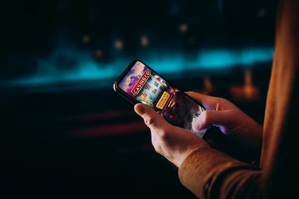 TAKABETBD মেম্বার লগইন — ফিরে যান আপনার ব্যক্তিগত ড্যাশবোর্ডে ক্যাসিনো-থিমযুক্ত ব্যাকগ্রাউন্ডে কেউ তার ডিভাইস ব্যবহার করছেন—যা TAKABETBD–এ মসৃণভাবে অ্যাকাউন্টে পুনরায় প্রবেশের অভিজ্ঞতাকে তুলে ধরে।